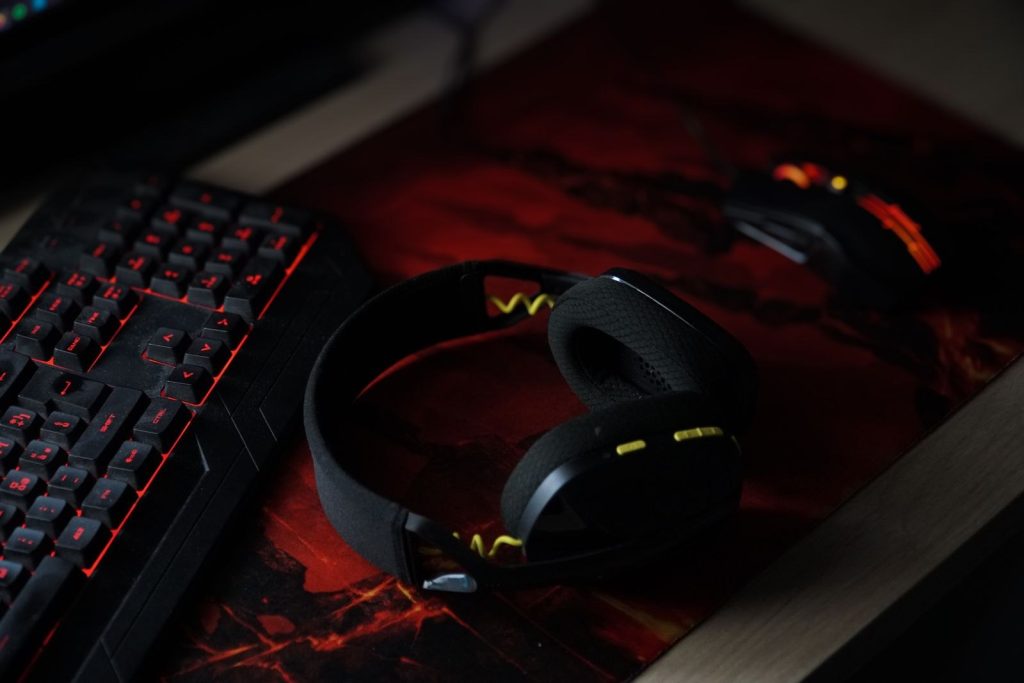 Headphones resting beside a backlit keyboard and mouse