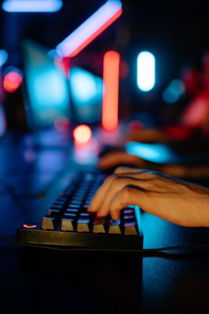 Hands using a keyboard in a colourful gaming room