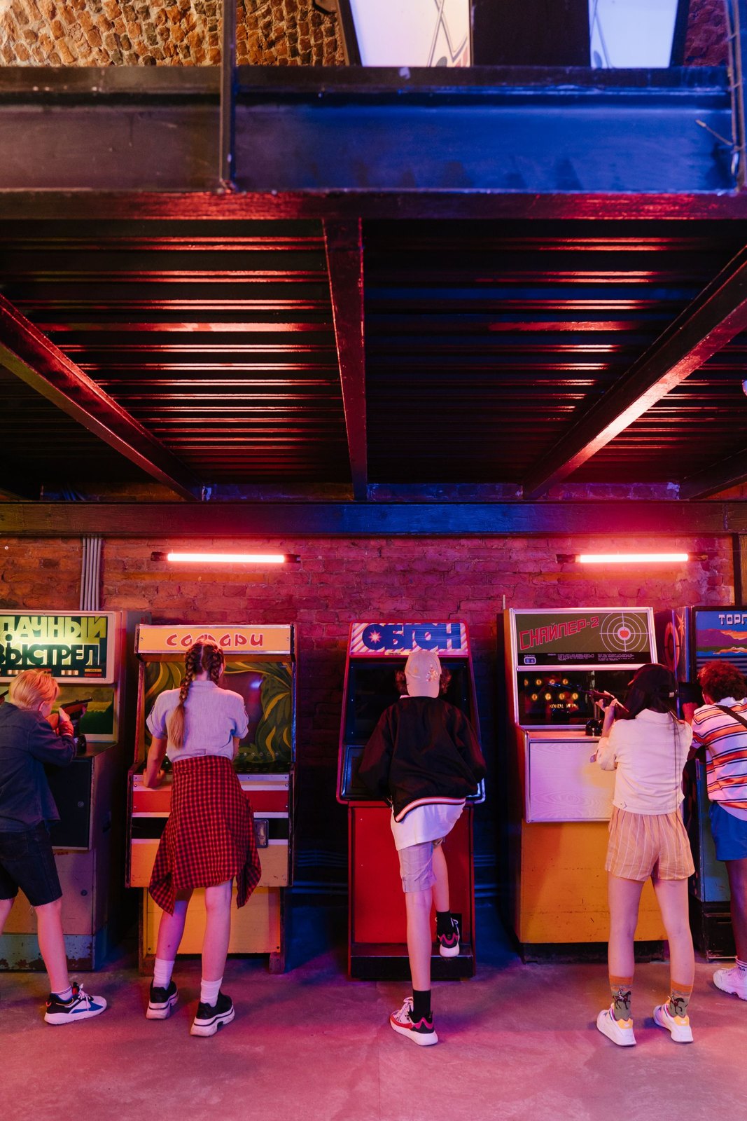 People playing at retro arcade cabinets in a colourful game room